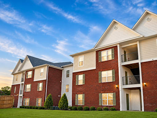 A red brick apartment building with a white trim and a balcony on the second floor.