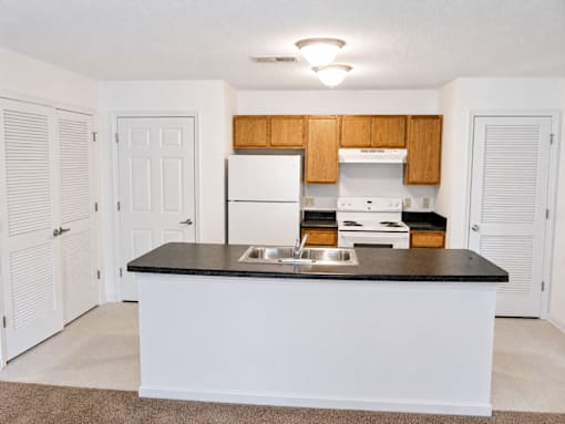 A kitchen with white appliances and wooden cabinets.
