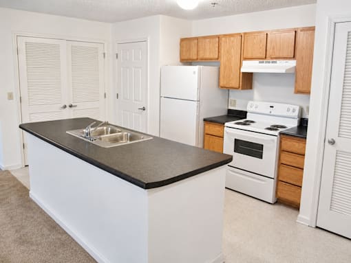 A kitchen with white appliances and wooden cabinets.