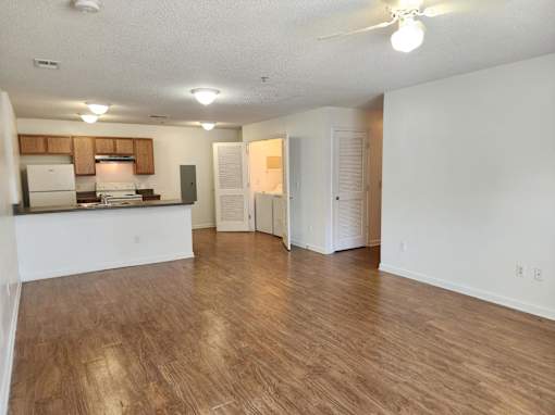 A spacious living room with hardwood floors and a ceiling fan.
