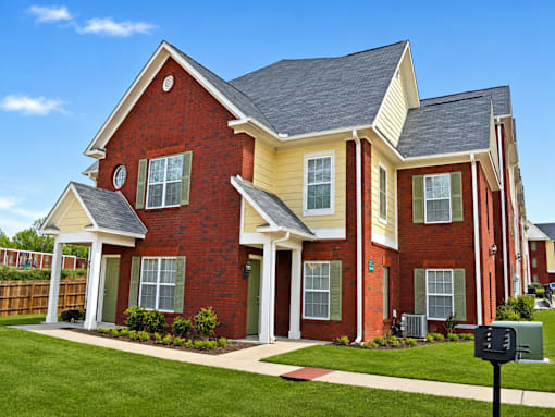 A red brick house with a white roof and a mailbox in front.