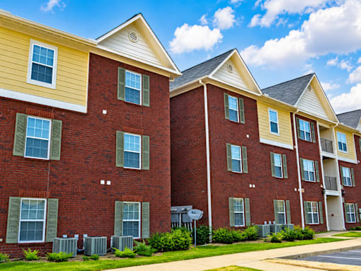 A row of red brick apartment buildings with green shutters on the windows.