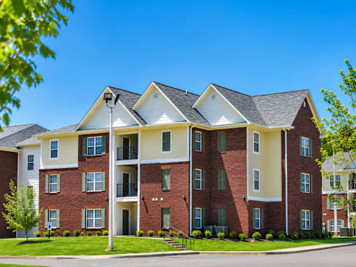 A large red brick apartment building with a white trim and a black roof.