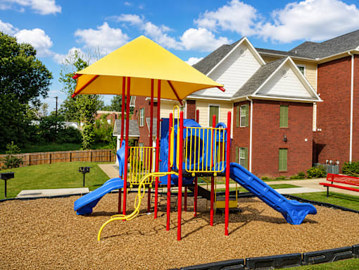 A playground with a yellow umbrella and a blue slide.