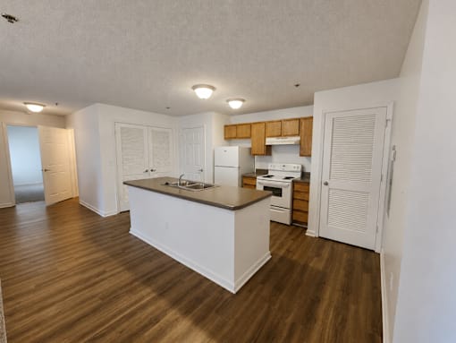 A kitchen with white cabinets and a wooden floor.