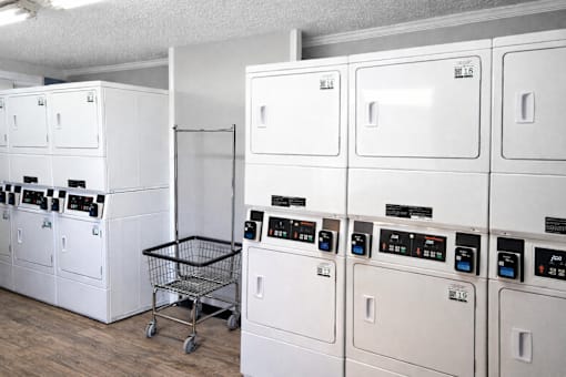 A laundry room with a shopping cart and washing machines.