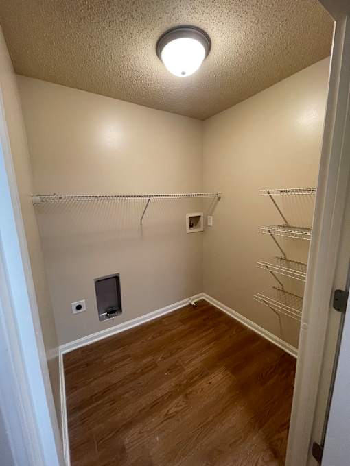 A small room with a wooden floor and a white ceiling with a light fixture.