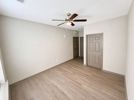 A room with a ceiling fan and a door.