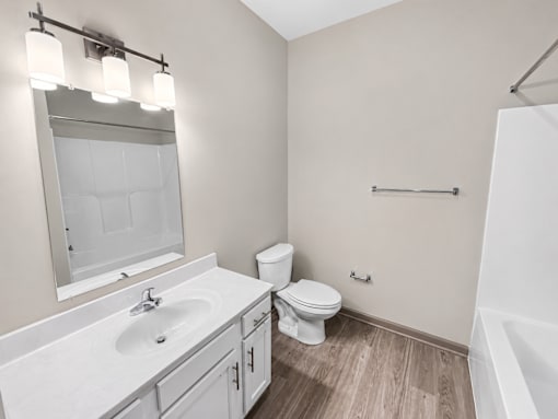 A white bathroom with a toilet, sink, and mirror.