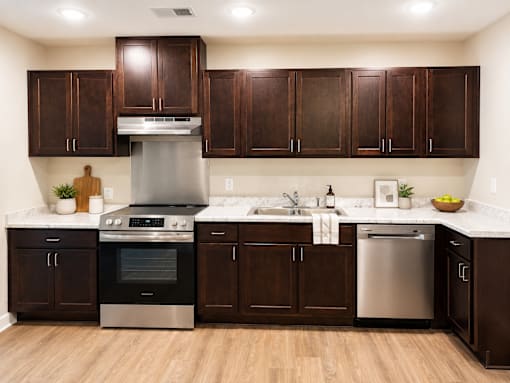 A modern kitchen with dark wood cabinets and stainless steel appliances.