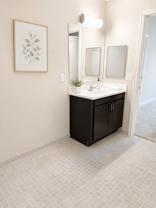 A bathroom with a black vanity and a framed leaf picture on the wall.