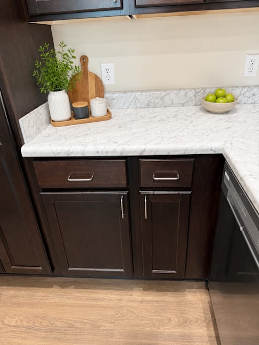 A kitchen with dark brown cabinets and a marble countertop.