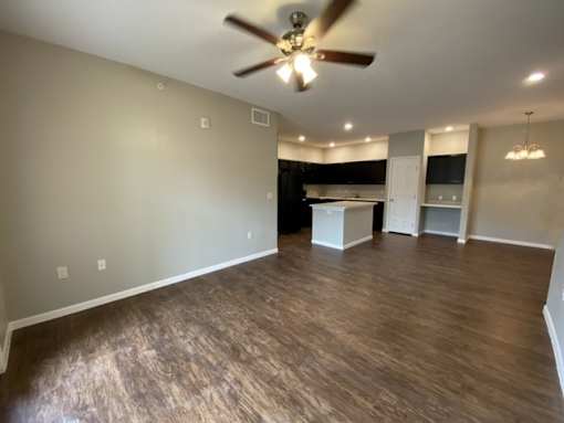A room with a ceiling fan and wooden flooring.