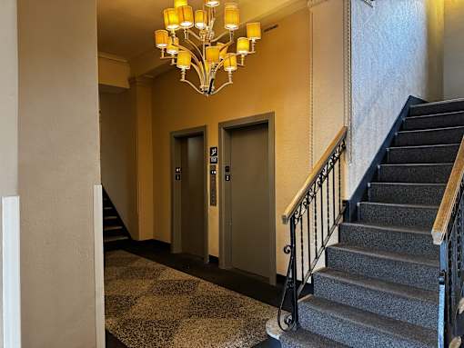 A staircase with a black metal railing and a chandelier hanging from the ceiling.