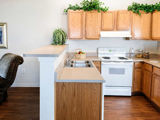A kitchen with wooden cabinets and a white stove top oven.