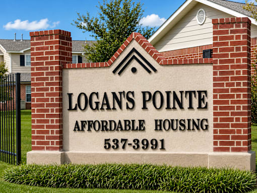 A sign for Logan's Pointe Affordable Housing stands in front of a house.
