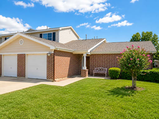 A house with a white garage door and a brick wall.