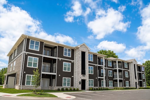 A large, modern apartment building with multiple balconies and doors.