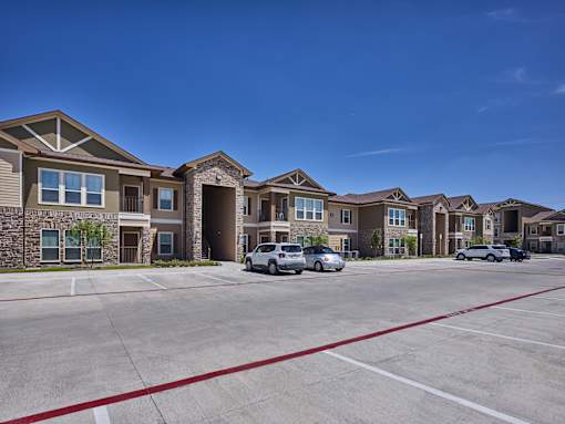A row of houses with cars parked in front.