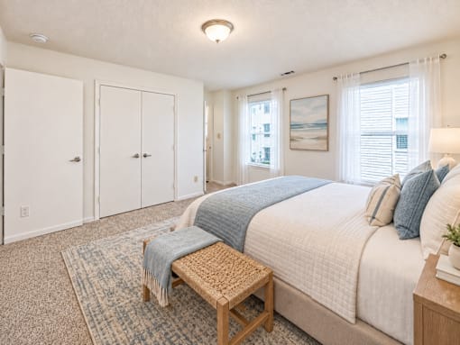 A bedroom with a bed, a bench, and two doors.