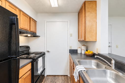A kitchen with a black fridge and wooden cabinets.