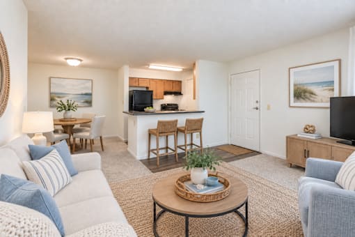 A living room with a white couch, a coffee table, and a flat screen TV.