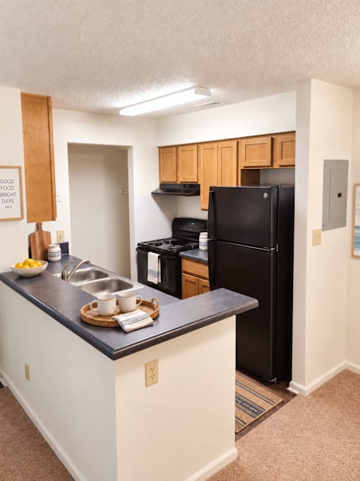 A kitchen with a black fridge and white cabinets.