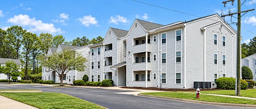 A large white apartment building with a tree in front of it.