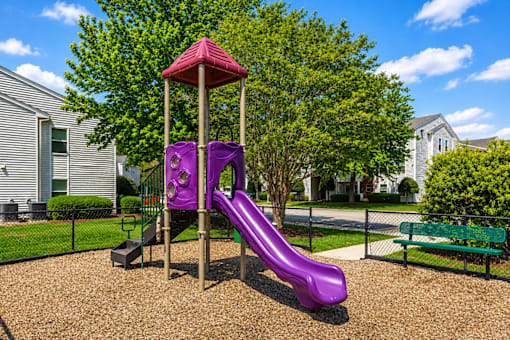 A purple slide in a playground with a red roof.