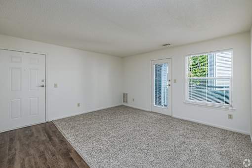 A room with a carpeted floor and a window with blinds.