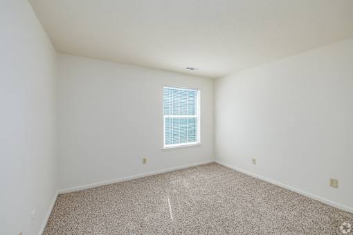 A room with a window and carpeted floor.