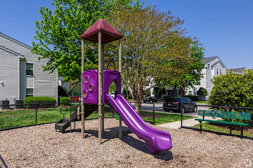 A purple slide in a playground with a red roof.