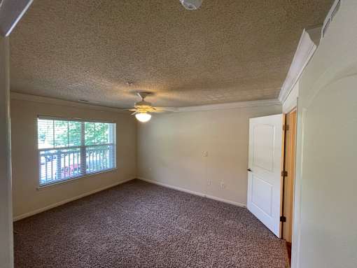 A room with a carpeted floor and a window with blinds.