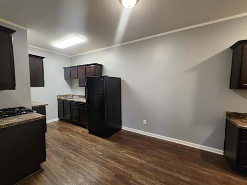 A kitchen with a black fridge and wooden floors.