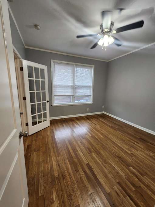 A room with a ceiling fan and wooden flooring.