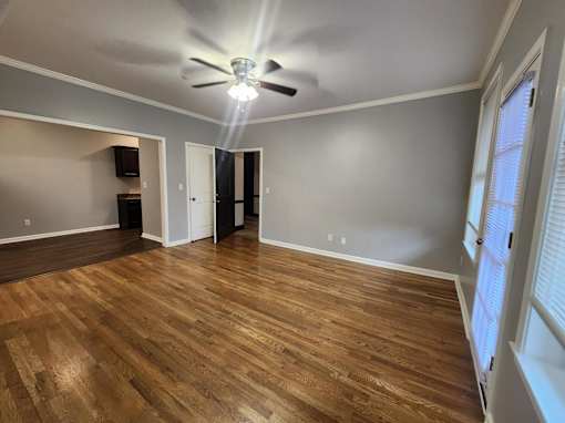 A room with a ceiling fan and wooden flooring.