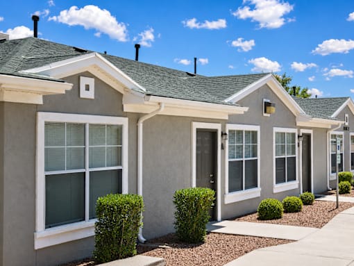 A row of houses with grey walls and white windows.