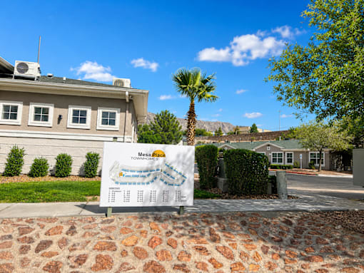 A sign for Mesa Pizza is displayed in front of a house.