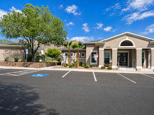 A parking lot in front of a building with a palm tree.