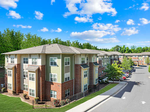 Apartment complex with a green lawn and a clear blue sky.