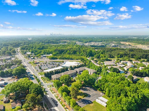 A bird's eye view of a residential area with houses, trees, and a road.