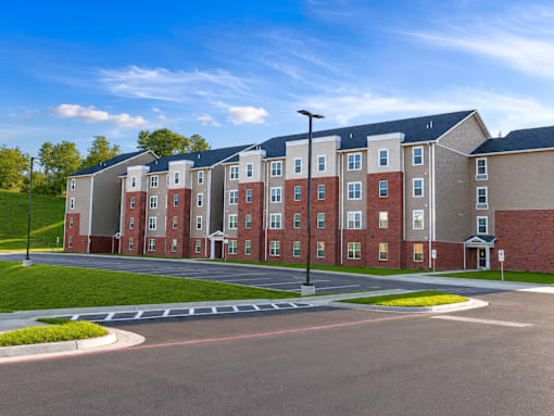 A large apartment complex with a parking lot in front.