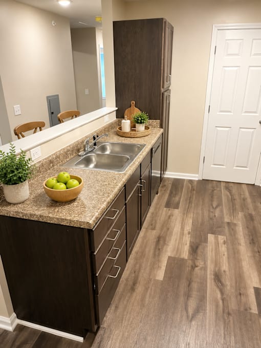A kitchen with a wooden floor and a white door.