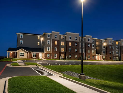 A streetlight stands in front of apartment buildings at dusk.