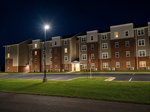 Apartment building at night with lights on.