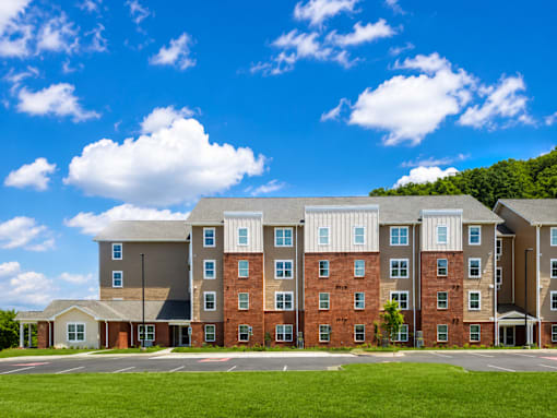 A large multi-story apartment building with a green lawn in front.