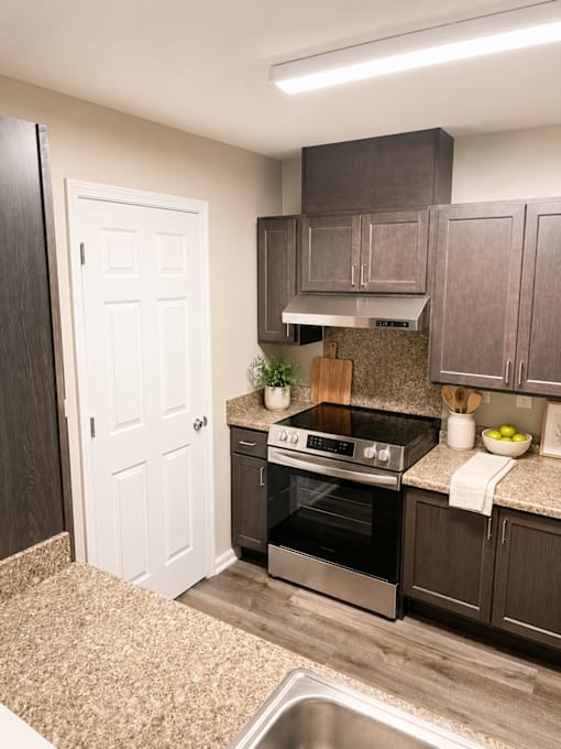 A kitchen with a stove top oven and a white door.