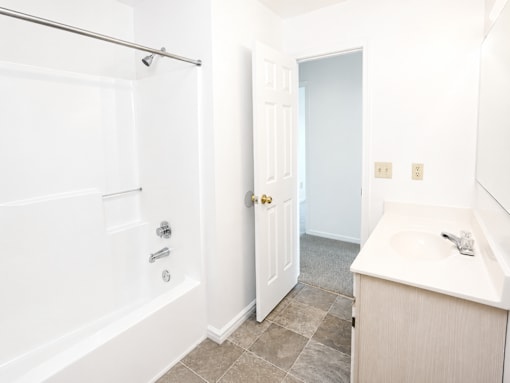 A white bathroom with a tub, sink and toilet.