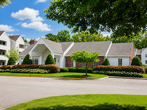 A large white house with a grey roof and a green lawn in front.