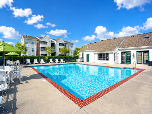 A large swimming pool with a red border and white lounge chairs.